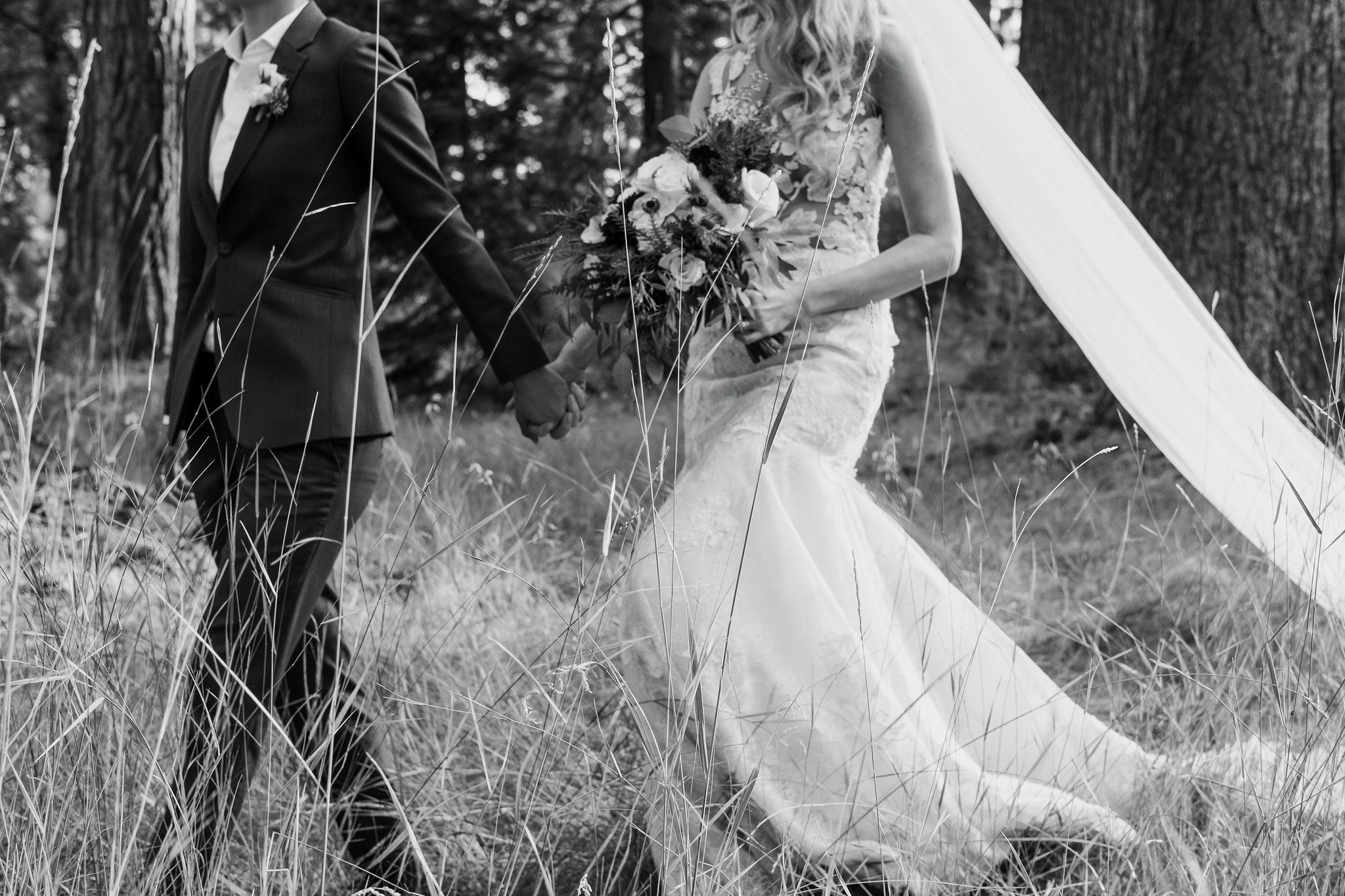 couple walks through forest on wedding day