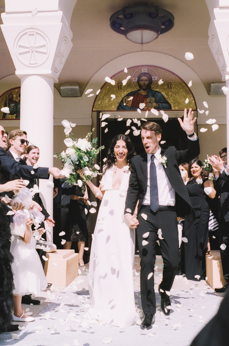 just married couple exiting church with flowers being thrown